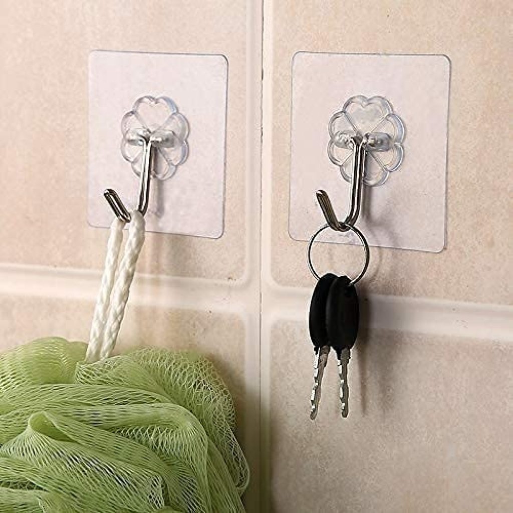 Clear adhesive hooks on a tiled wall with a loofah and keys attached.